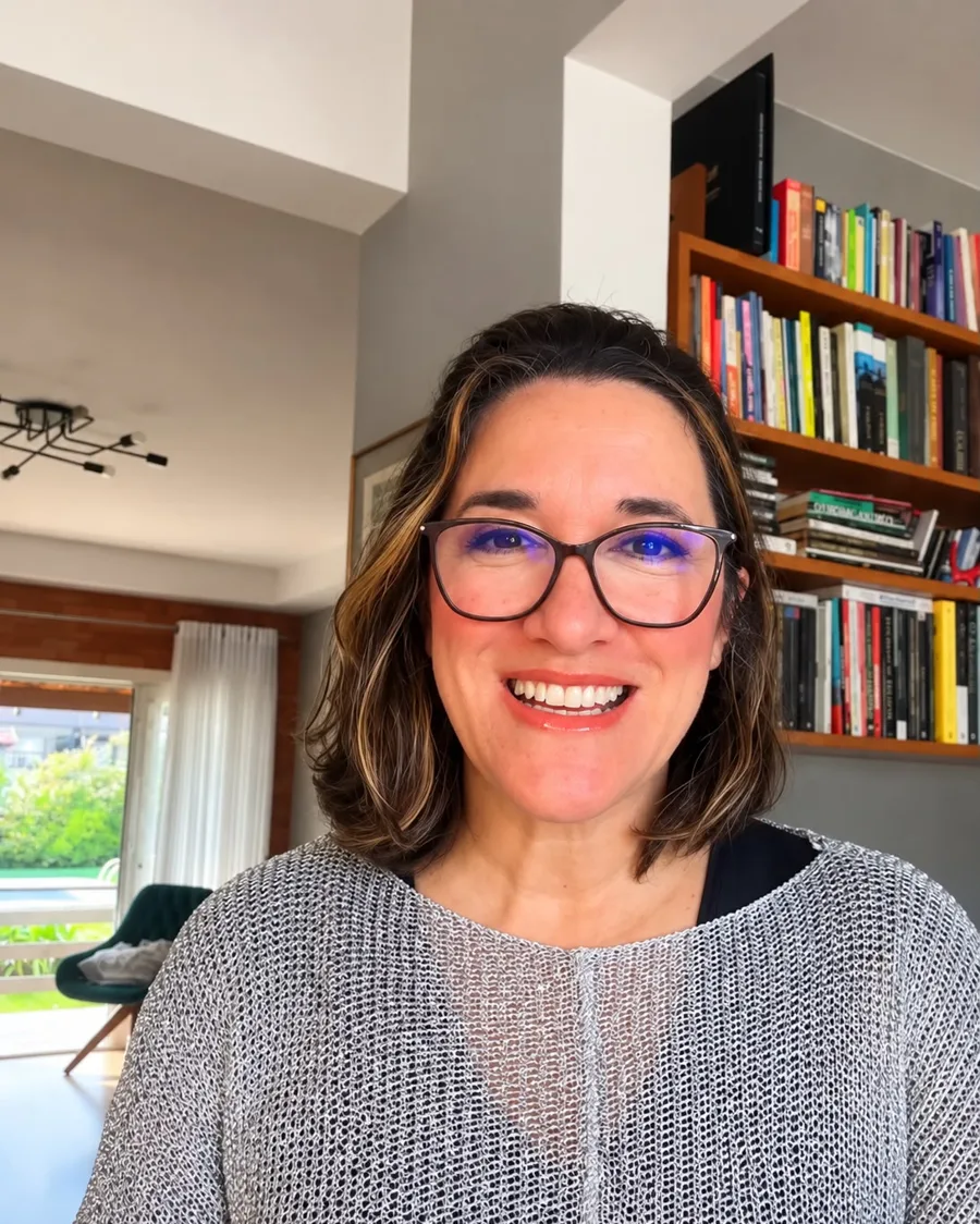 Gaba Costa, idealizadora do SIMEDUC, sorrindo em frente a uma estante de livros